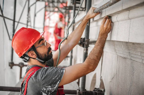 Mann steht auf Gerüst und restauriert alte Hausfassade — Stockfoto