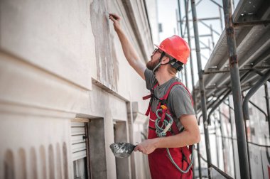 İnşaat işçisi, eski bina duvarını çimento alçısıyla kaplıyor. 