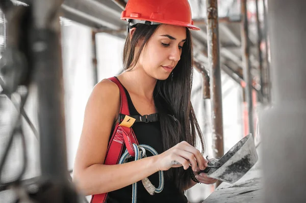 Female construction mason on the scaffolding, plastering and renovating building