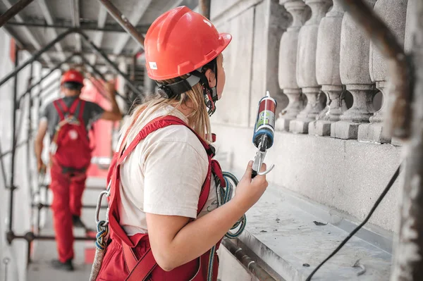 Albañil de construcción hembra en el andamio, trabajando con pistola de silicona — Foto de Stock