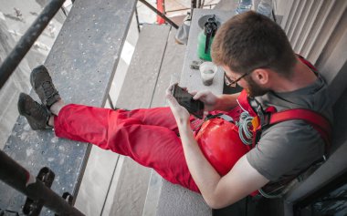 İskeledeki inşaat işçisi cep telefonu kullanıyor.