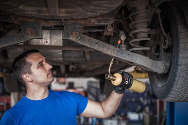Araba ustası tamirci vidaları alev topuyla ısıtıyor.