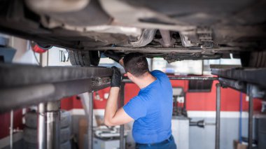 Otomatik tamirci aracın altındaki durumu kontrol ediyor.