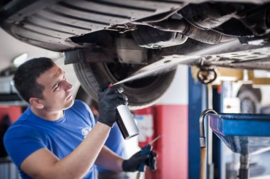 Otomobil ustası tamircisi vidaları makine temizleyicisiyle yağlıyor