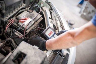 Araba tamircisi ba ile otomotiv akümülatörünü kontrol ve test ediyor