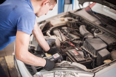Araba tamircisi ba ile otomotiv akümülatörünü kontrol ve test ediyor