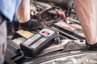 Araba tamircisi ba ile otomotiv akümülatörünü kontrol ve test ediyor