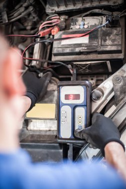 Araba tamircisi ba ile otomotiv akümülatörünü kontrol ve test ediyor
