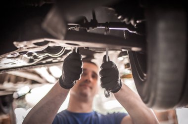 Otomatik tamirci aracın altındaki durumu kontrol ediyor.