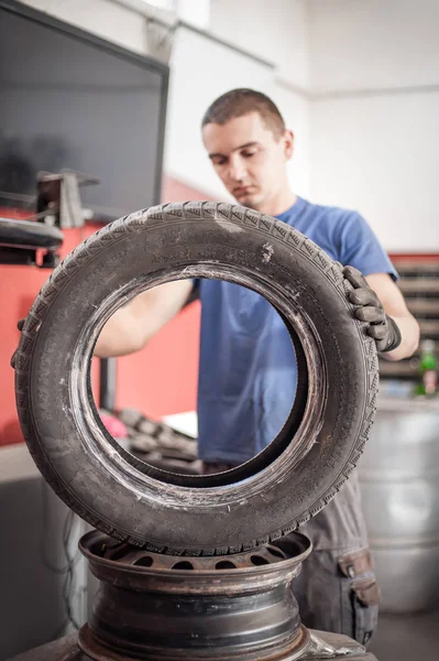 Automechaniker ersetzt alte Reifen und wechselt sie durch neue aus — Stockfoto