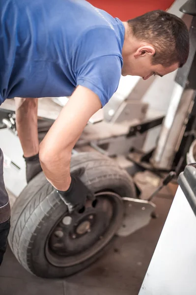Automechaniker ersetzt alte Reifen und wechselt sie durch neue aus — Stockfoto