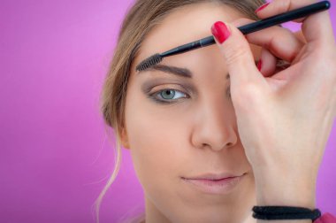 Makyaj sanatçısı model e 'nin kirpiklerine rimel sürüyor
