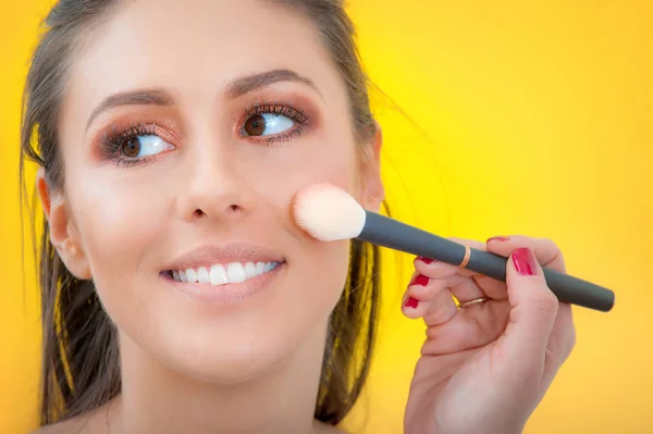 Artista de maquillaje aplicando maquillaje en su cara usando pincel de polvo — Foto de Stock