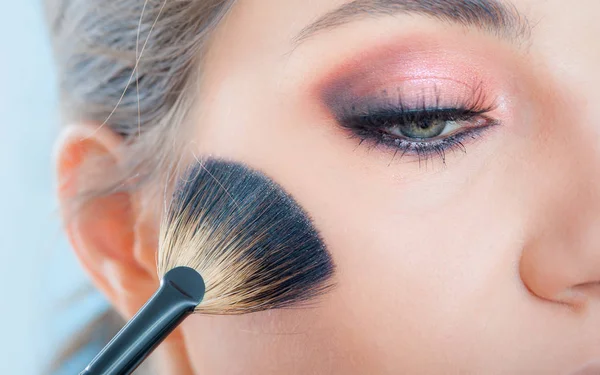 Artista de maquillaje aplicando maquillaje en su cara usando pincel de polvo —  Fotos de Stock