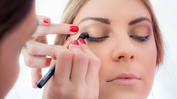 Makeup professional artist applying base color eyeshadow on mode