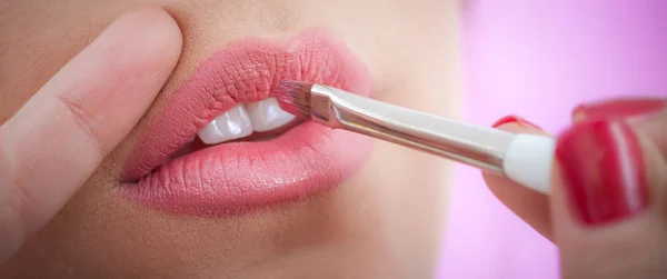 Maquillaje artista profesional aplicando lápiz labial a los labios modelo — Foto de Stock