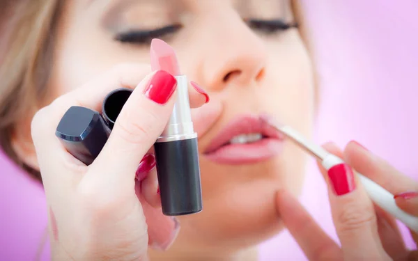 Maquillaje artista profesional aplicando lápiz labial a los labios modelo — Foto de Stock
