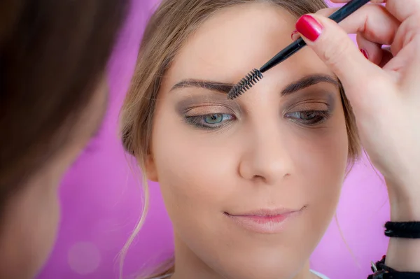 Maquillaje artista profesional aplicando rímel en las pestañas de la modelo e — Foto de Stock