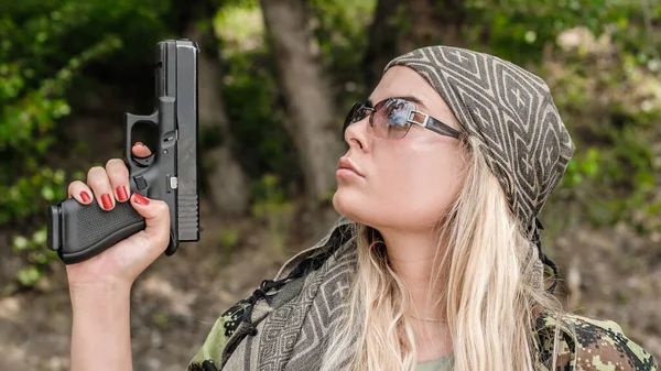 Beautiful and attractive female army soldier posing with gun. Woman with weapon. Firearm shooting range gun shooting training. Fashion model style