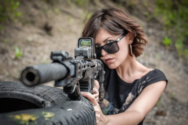 Beautiful and attractive woman soldier shooting with rifle machine gun from behind and around cover or barricade. Female  army military combat training on the shooting range