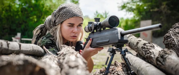 Female soldier shooting with sniper rifle. Woman with weapon. Firearm army shooting and tactical training. Outdoor shooting range