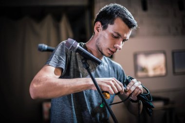 Tiyatro teknisyeni olay yerinde mikrofon ayarlıyor. Ses sistemi arkaplanda kuruluyor ve test ediliyor