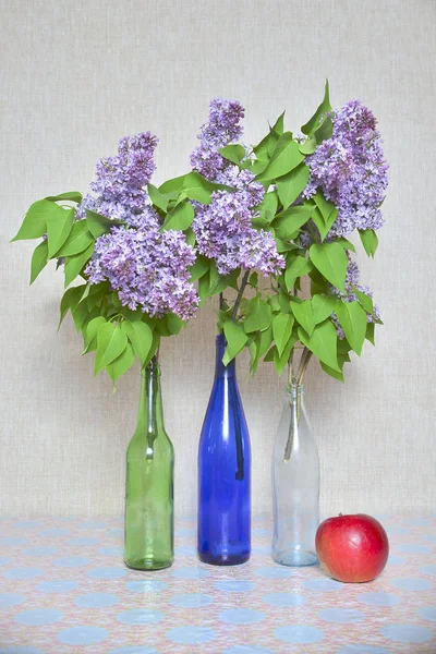 Bouquets of lilacs and red apple