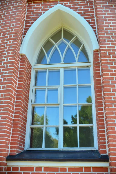 White painted wood arched window in a red brick wall