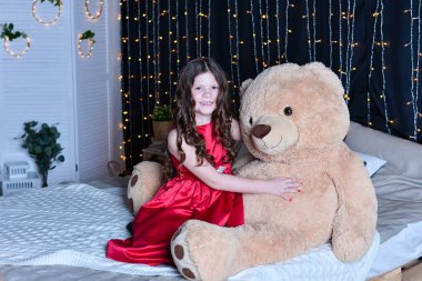 Evde yatakta oyuncak ayı ile güzel kız 