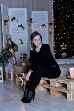 Genç ve güzel bir kadın evde yatakta oturuyor.