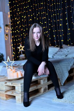 Genç ve güzel bir kadın evde yatakta oturuyor.