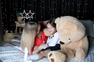 Güzel kız ve Anne oyuncak ayı ile yatak odasında poz 