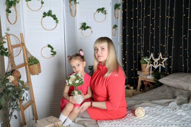 Güzel kız ve annesi çiçek ile yatak odasında poz 