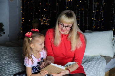 Güzel kız ve onun anne okuma kitap içinde yatak odası 