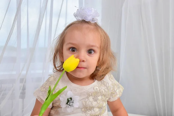 屋内に黄色いチューリップを持つ小さな女の子 — ストック写真