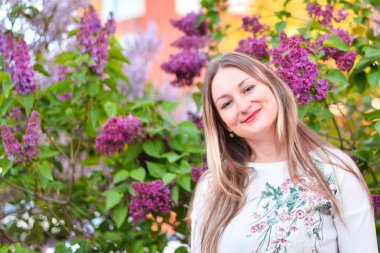 Çiçekli bahçesinde uzun sarı saçlı kadın. Güneşli bir güzel kız.