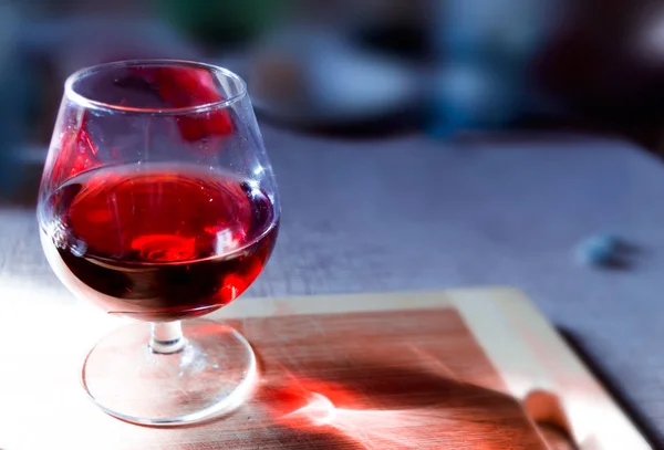 Sklenice na víno s červeným vínem na dřevěné desce s rozmazaným pozadím. — Stock fotografie