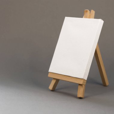 Gri arka plan üzerinde şelon üzerinde boş beyaz tuval