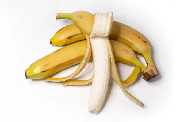 Três bananas maduras, uma sem pele em um fundo isolado branco . — Fotografia de Stock