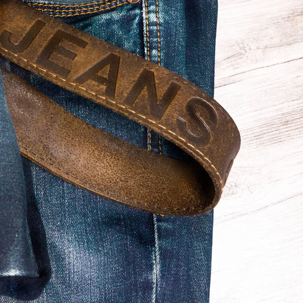Alte Jeans mit Ledergürtel auf hölzernem Hintergrund — Stockfoto