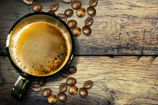 Vista superior de uma xícara de café em uma mesa velha de madeira e grãos de café — Fotografia de Stock