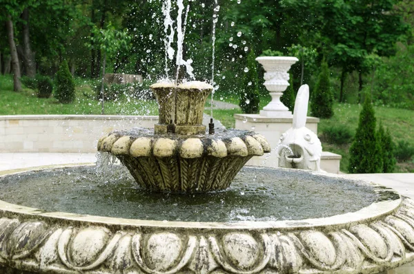 Old fountain sprays water in different directions — Stock Photo, Image