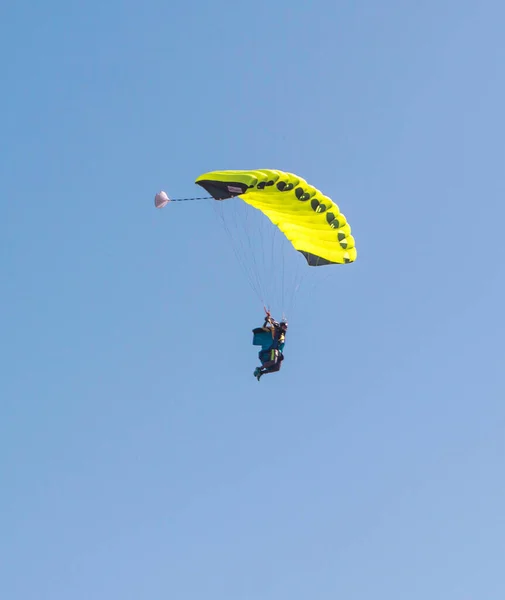 Yellow parachute against the blue sky with a skydiver. — Stock Photo, Image