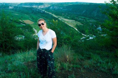 Gözlüklü kadın bir uçurumun kenarında gülümsüyor..