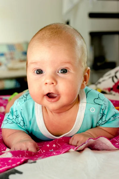 Il bambino incantevole in sorrisi azzurri e si trova su uno stomaco — Foto Stock