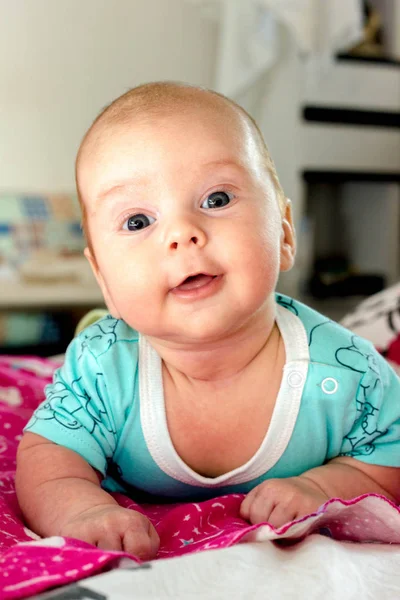 Urocze dziecko w niebieski uśmiechy i leży na żołądku — Zdjęcie stockowe