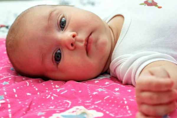 Lindo bebé niño acostado y mirando a la cámara en el fondo violeta —  Fotos de Stock