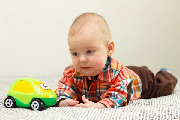 El niño está jugando con una camisa verde a cuadros de coche. —  Fotos de Stock