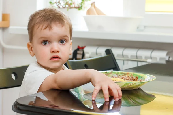 Le gamin est assis à une table à manger dans la cuisine légère — Photo