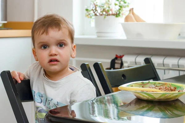 Le gamin est assis à une table à manger dans la cuisine légère — Photo